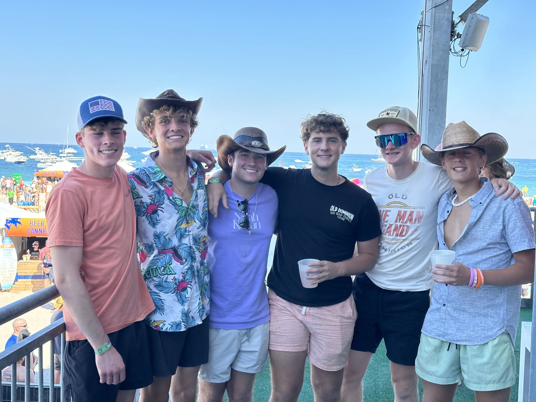 Six friends in cowboy hats at a beach music festival